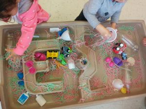 Playing with cooked and coloured spaghetti and assorted plastic containers.